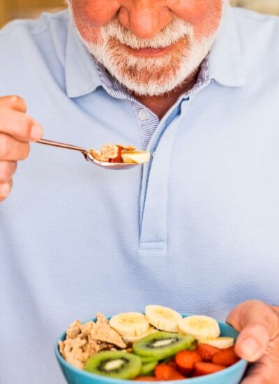 Smiling elderly man holding a bowl of fresh and dried fruits. healthy eating at breakfast